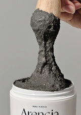 Gray putty being scooped from a container labeled 'Arencia' with a wooden tool.