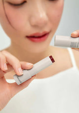Person holding a tube of lipstick with a blurred background