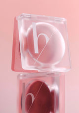 Pink lip balm in a clear container on a pink background