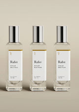 Three Rafer perfume bottles with silver caps on a beige background