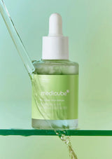 Medicube skincare serum bottle with dropper on a green background