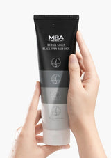 Hand holding a black hair pack tube labeled 'MBA' against a white background