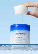 Medicube Zero Pore Pad container with a hand holding a white pad against a blue background