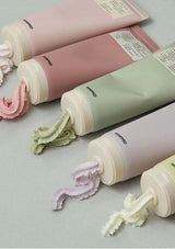 Multiple tubes of cream with visible textures on a light gray background