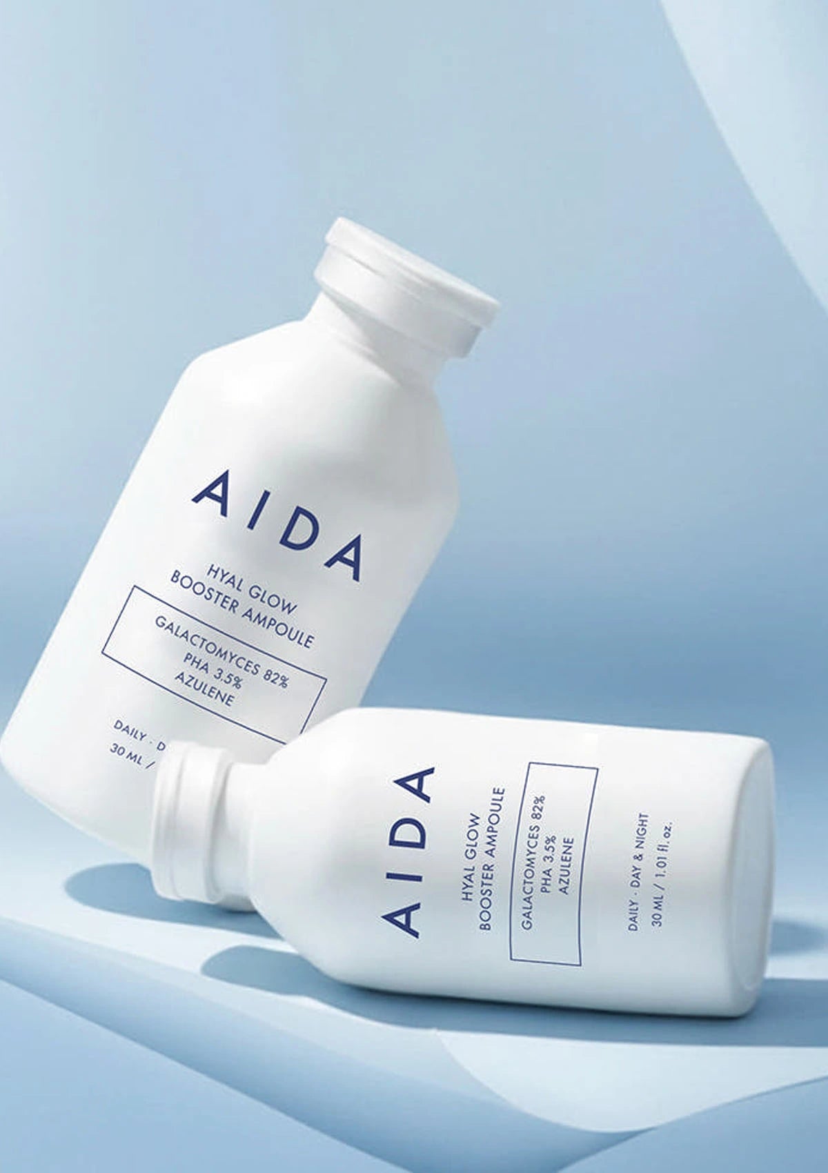 Two AIDA skincare bottles on a light blue background
