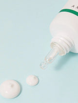 White dropper bottle with a green cap on a light blue background
