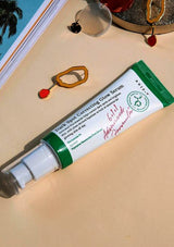 Tube of Axyly Dark Spot Correcting Glow Serum on a beige surface with decorative items.
