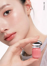 Close-up of a woman holding a pink lip balm with a neutral background