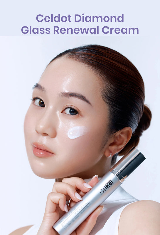 A woman with her hair pulled back holds a silver and black Celdot Diamond Glass Renewal Cream tube against a light background, with a white cream swatch on her cheek and purple text at the top reading 'Celdot Diamond Glass Renewal Cream'.