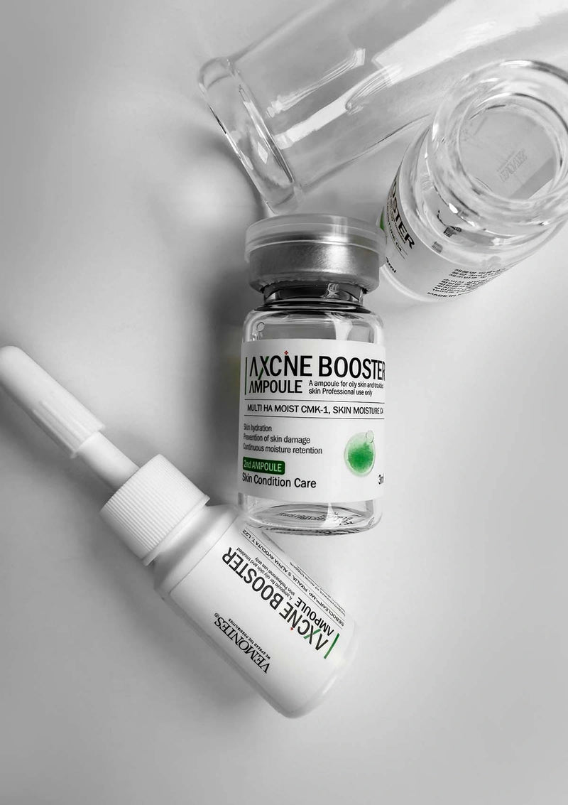 Skincare products including a bottle and ampoule on a light gray background