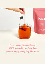 Tea bag being added to a glass of tea with 'Odad' packaging in the background.