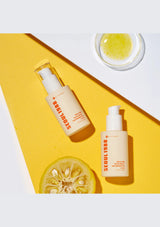 Two skincare bottles with a lemon on a yellow and white background