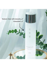 Skincare bottle with text indicating texture, viscosity, and scent on a white background with green leaves.