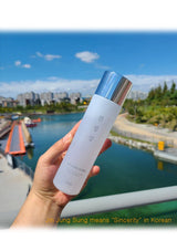 Hand holding a skincare bottle with a scenic background