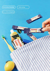 Blanx toothpaste and strips on a blue background with a hand holding a striped bag.