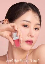 Woman holding a pink lip tint with a pink background