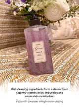 Purple bottle of 'Green' cleanser on a textured surface with flowers in the background