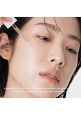 Close-up of a person applying a skincare product to their face with a dropper.