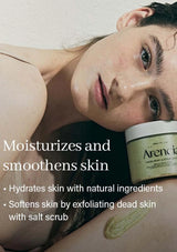 Woman lying down with a jar of Arencia body scrub on her leg, text highlighting product benefits.