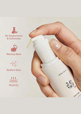Hand holding a white skincare bottle with text on a light background