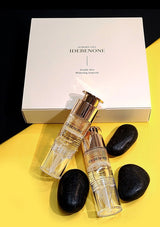 Two IDEBENONE skincare bottles on a yellow surface with a white box in the background.