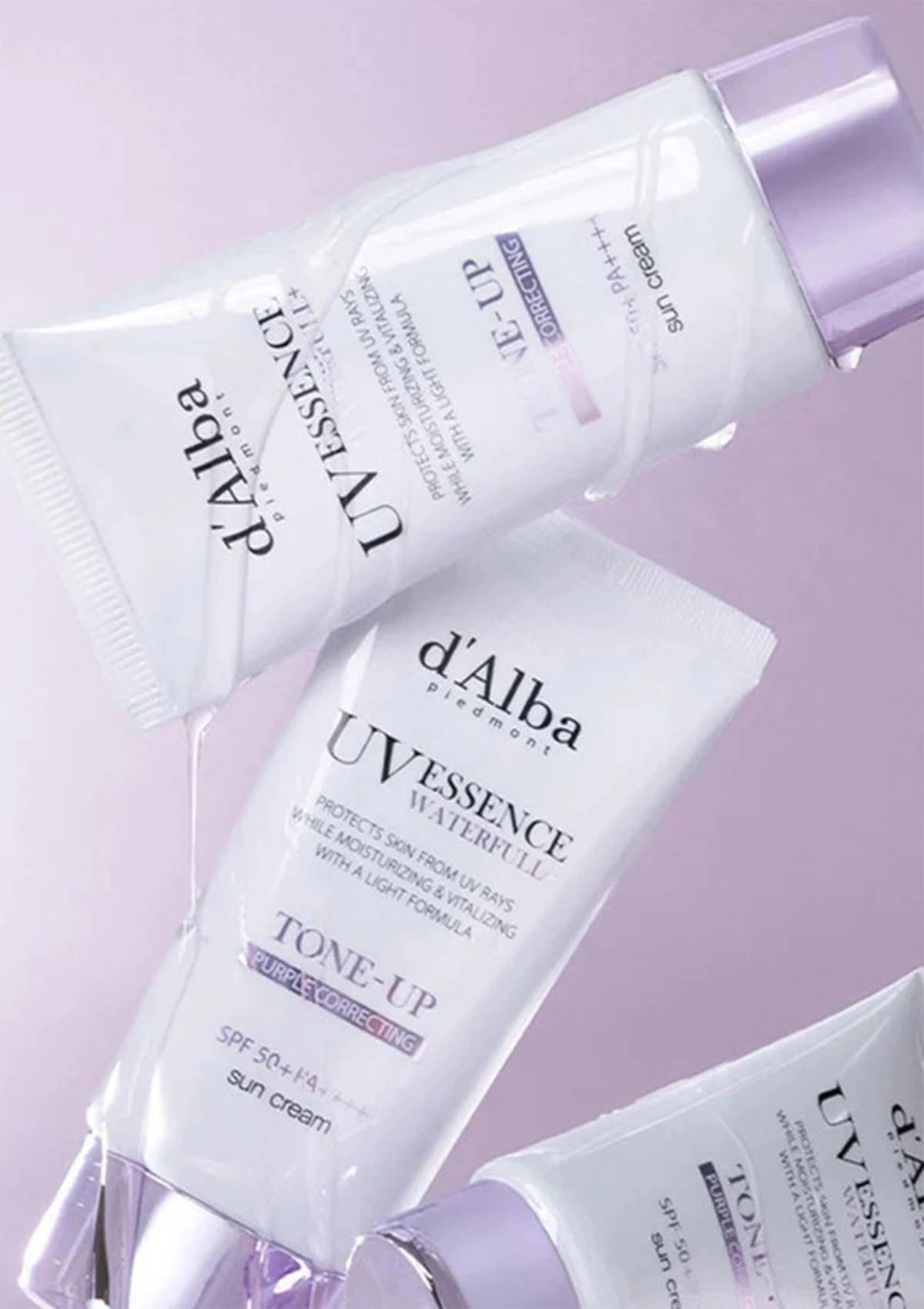 d'Alba UV Essence watermelon skincare products on a light purple background