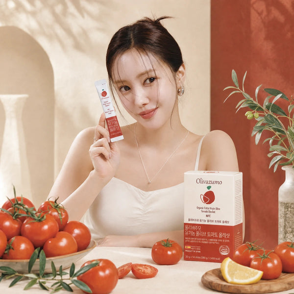 Woman holding an OLIVAZUMO tomato sachet beside the box and fresh tomatoes
