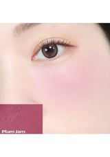 Close-up of a brown eye with a pinkish background, featuring the brand 'Plum Jam'.