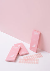 Pink packaging and sheets on a white surface with a pink background