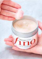 Jar of 'fino' cream with a hand applying it on a light background