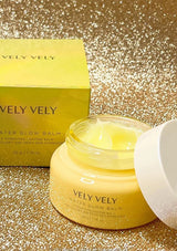 A jar of Vely Vely Water Glow Balm, with a yellow-gold colored product visible through the transparent glass.