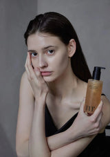 Woman holding a bottle of hair care product against a neutral background