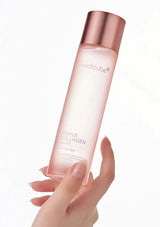 Hand holding a pink skincare bottle labeled 'medicube' on a white background