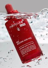 Red skincare product packaging with water droplets on a gray background