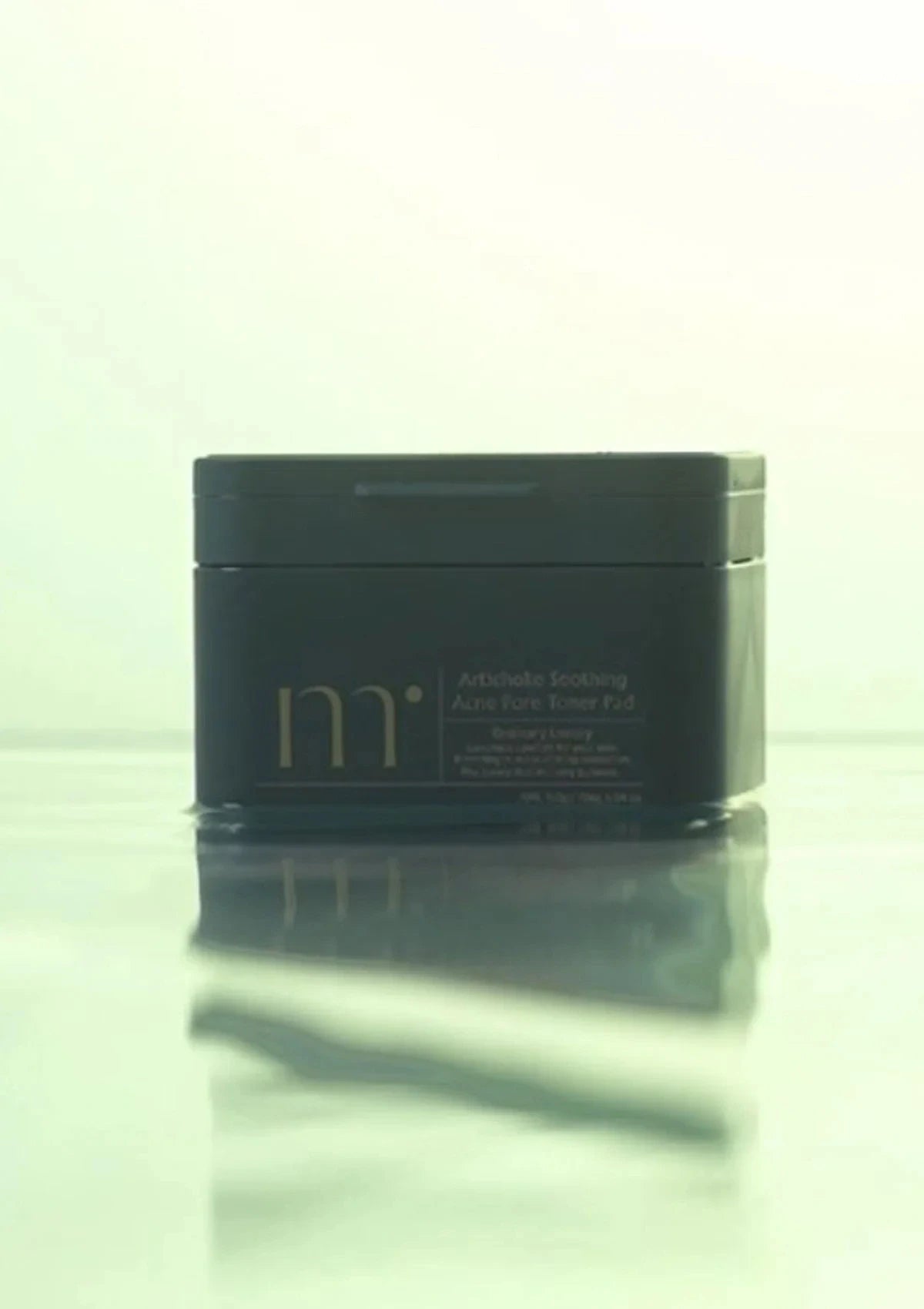 Black container with 'm' branding on a reflective surface