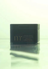 Black container with 'm' branding on a reflective surface
