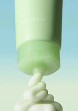 Green skincare product with cream being squeezed out on a gradient blue background