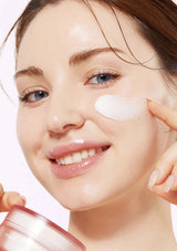 Woman applying cream to her face with a white background