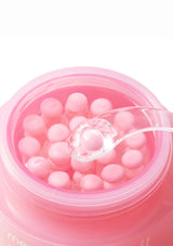 Pink container with pearl-like beads and a spoon on a white background