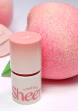 Tinted stick with pink cap and white body, next to a pink makeup sponge on a light background.