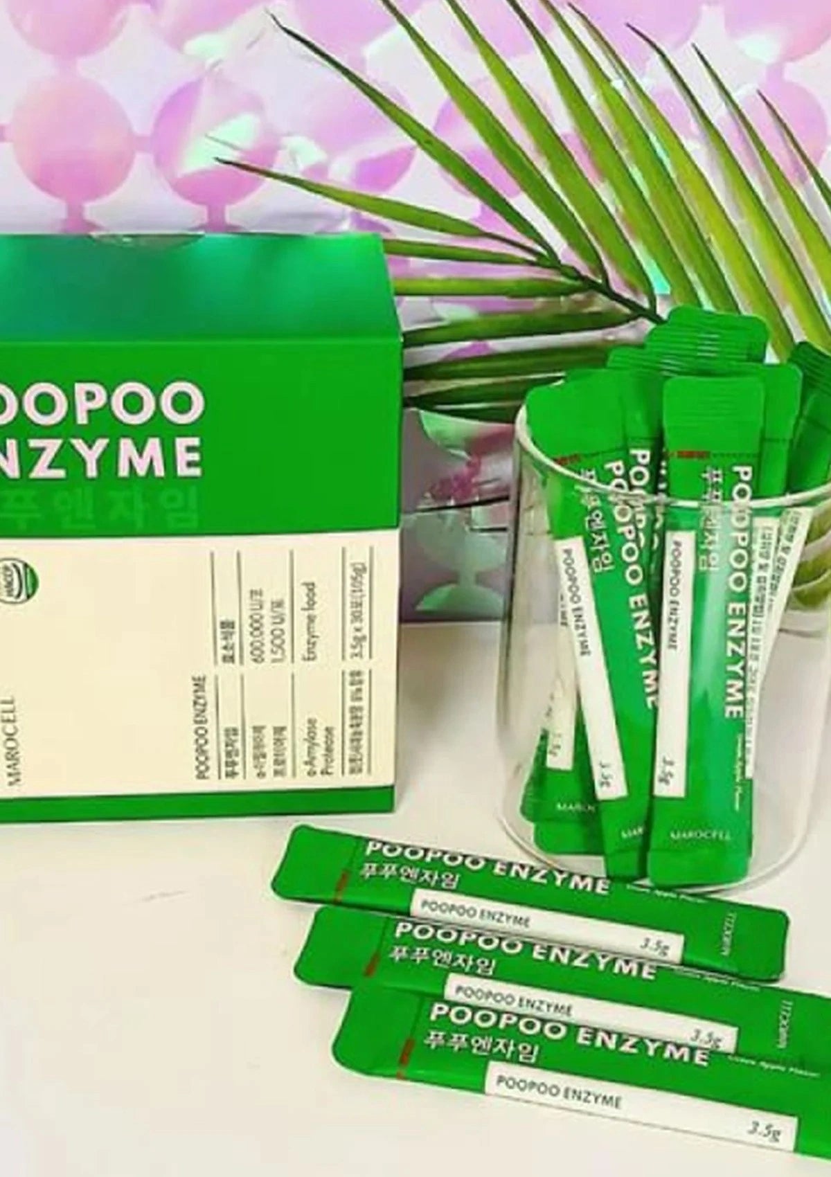 Green packets of Poopoo Enzyme with packaging on a white background