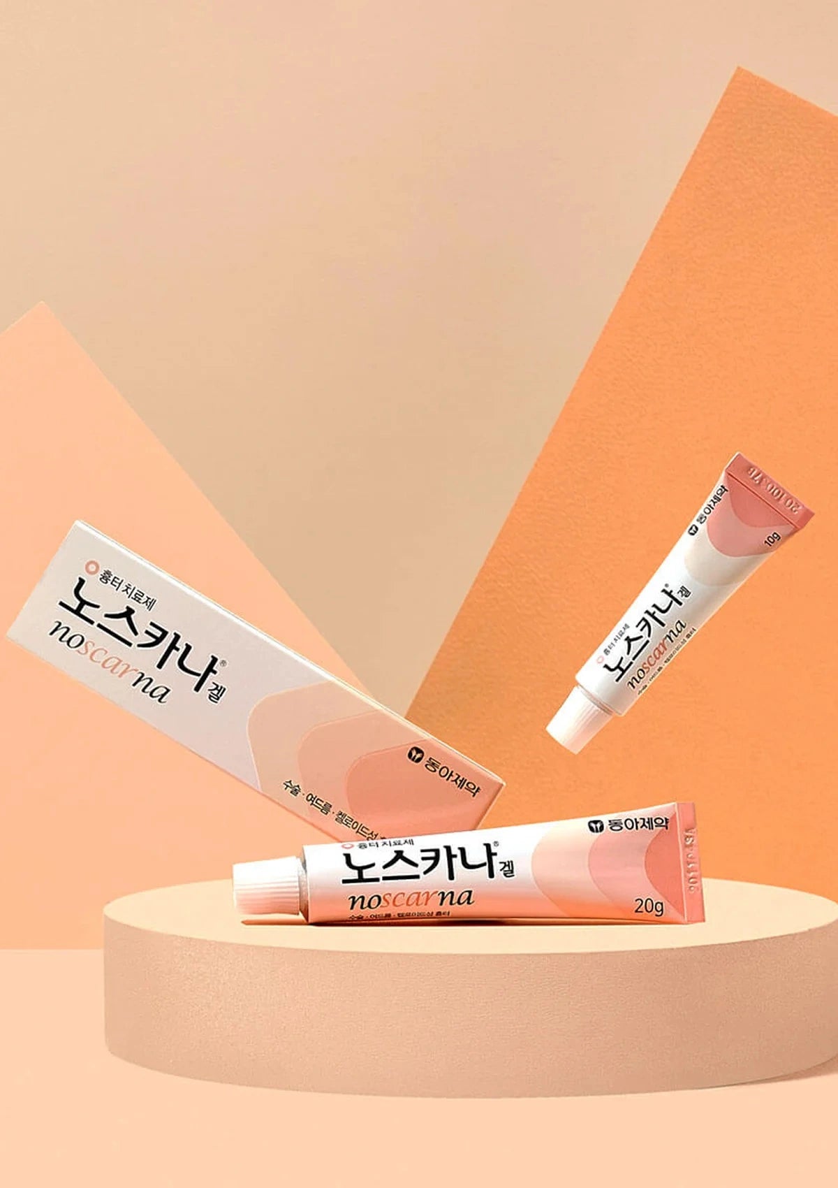 Three tubes of Noskana lip balm on a peach-colored platform with an orange geometric background