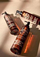 Three bottles of Bartera multi-action shaving foaming oil on a beige surface.