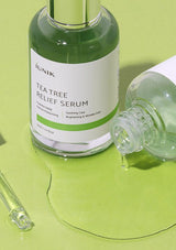 Tea tree relief serum bottle with dropper on a green background