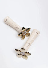 Two white tools with gold flower-shaped ends on a white background