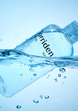 Torriden water bottle with water splashing around it on a blue background