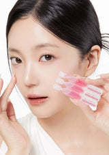 Woman holding a set of pink skincare products against a white background
