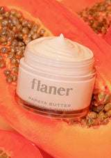 Jar of flaner papaya butter cream surrounded by papaya seeds on a bright background