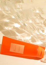 Orange bottle with a label on a textured beige background