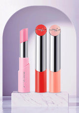 Three lipsticks with pink, red, and peach shades on a white platform with a purple arch background.